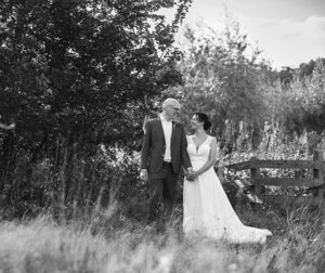 Zwart-witfoto van bruidspaar Anne en Harma die elkaar liefdevol aankijken in een natuurlijke omgeving, gefotografeerd door Fotografe Christha.