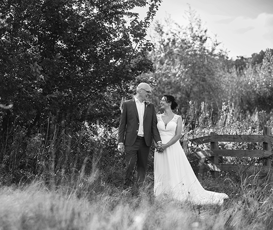 Zwart-witfoto van bruidspaar Anne en Harma die elkaar liefdevol aankijken in een natuurlijke omgeving, gefotografeerd door Fotografe Christha.