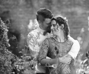 Een zwart-wit portret van de bruid en bruidegom die elkaar liefdevol omhelzen in de tuin van de Blokhuispoort.