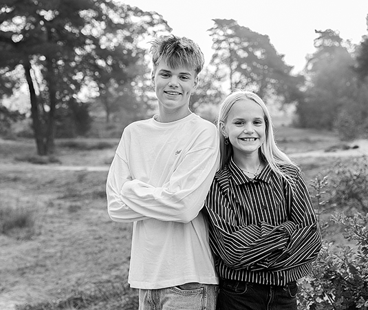 Zwart-wit portret van Jesse en Isa samen tijdens hun familiefotoshoot in de natuur bij Bakkeveen. De rustige achtergrond en het contrast van de zwart-witbewerking leggen de nadruk op de twee kinderen.