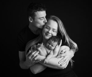 Ouders met pasgeboren baby tijdens een liefdevolle zwart-wit newbornshoot