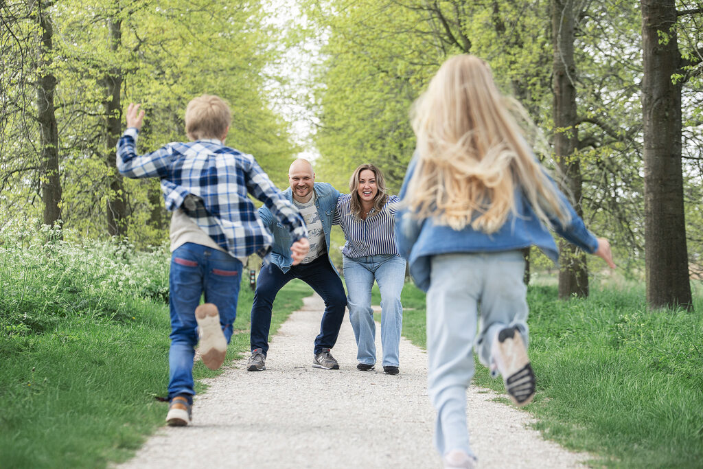 Kinderen rennen spontaan naar hun ouders, die met open armen en een glimlach op hen wachten in een groen natuurgebied.