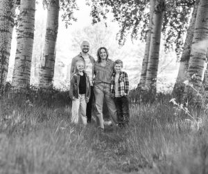 Gezin poseert samen in een natuurgebied in Leeuwarden, vastgelegd in zwart-wit met zachte contrasten en warme gezichtsuitdrukkingen.