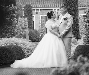 Bruidspaar Jolanda en Bauke kijken elkaar liefdevol aan in de tuin van het Sint Anthony Gasthuis.