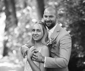 Bruid en bruidegom poseren liefdevol samen tijdens hun bruiloft in Leeuwarden, gefotografeerd door Fotografe Christha in de natuur van de Prinsentuin.