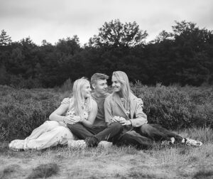 Zwart-wit portret van drie kinderen die samen op de heide zitten tijdens een familieshoot in Bakkeveen.