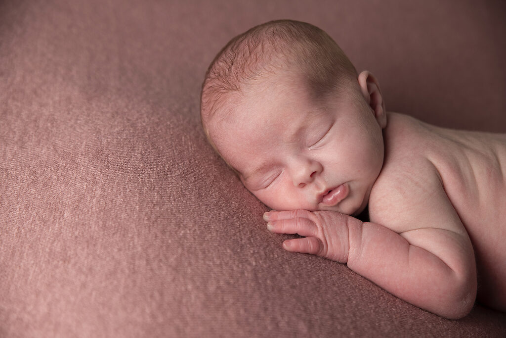 Pasgeboren meisje rustig slapend op een zachte ondergrond tijdens een professionele newbornshoot in Friesland.