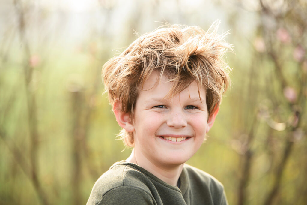 Portret van een jongen met warrig haar op het erf van Boer Bart tijdens een gezinsfotoshoot