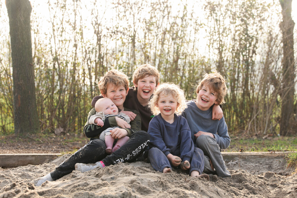 Vijf kinderen samen in de zandbak tijdens een gezinsfotoshoot bij Boer Bart