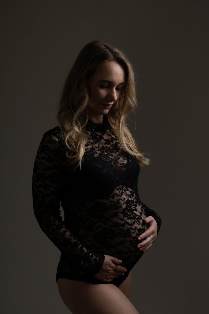Zwangere vrouw in zwarte kanten body tijdens zwangerschapsshoot in fotostudio Leeuwarden