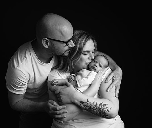 Zwart-wit foto van een pasgeboren baby met ouders tijdens een newborn fotoshoot in Leeuwarden.